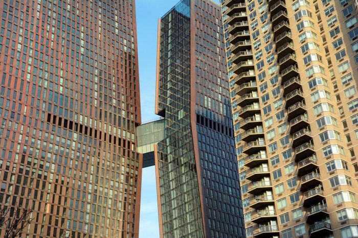 A glazed sky bridge connecting two high-rise towers above a city street