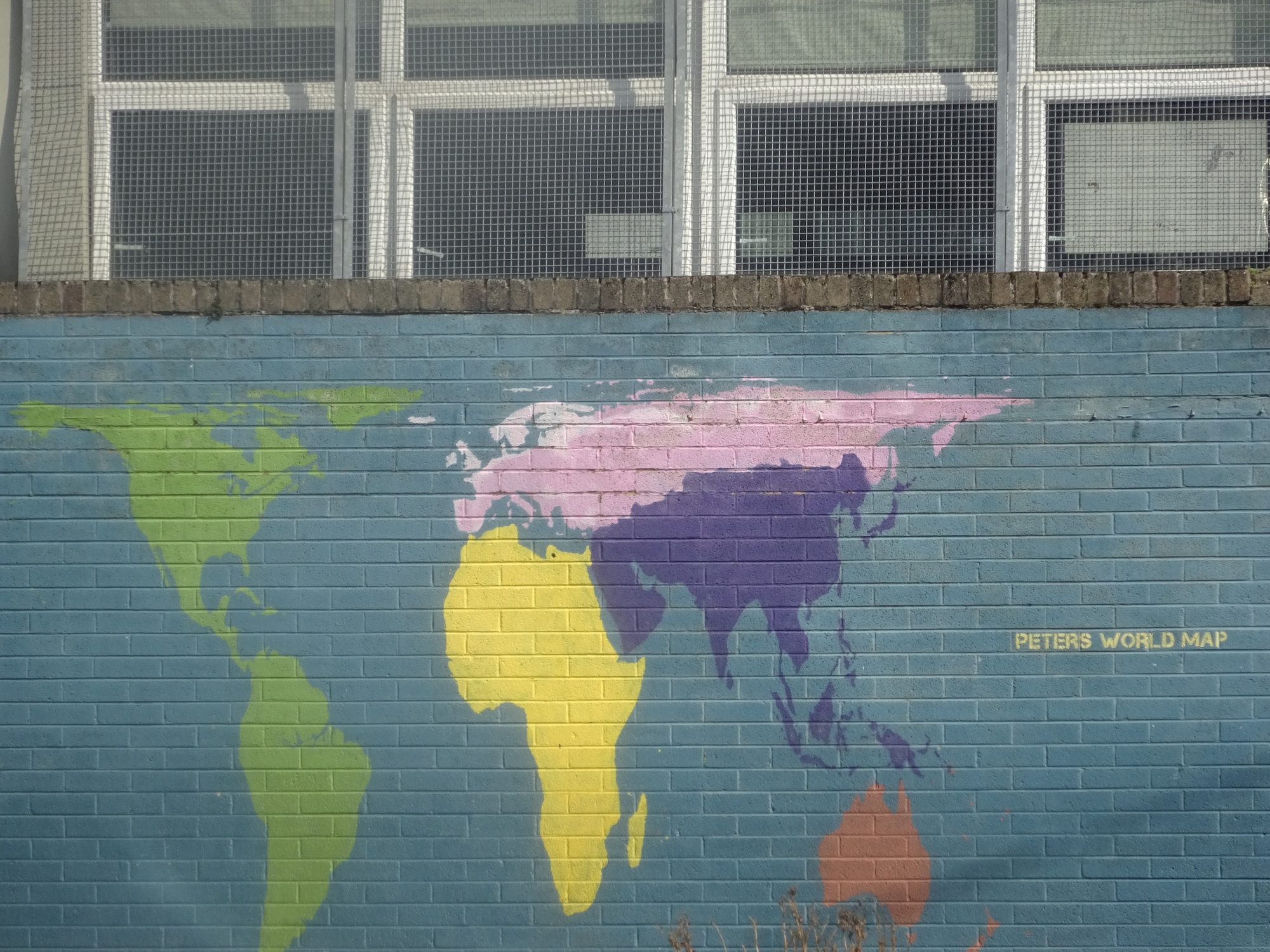 School wall mural showing the Gall Peters world map with continents in color