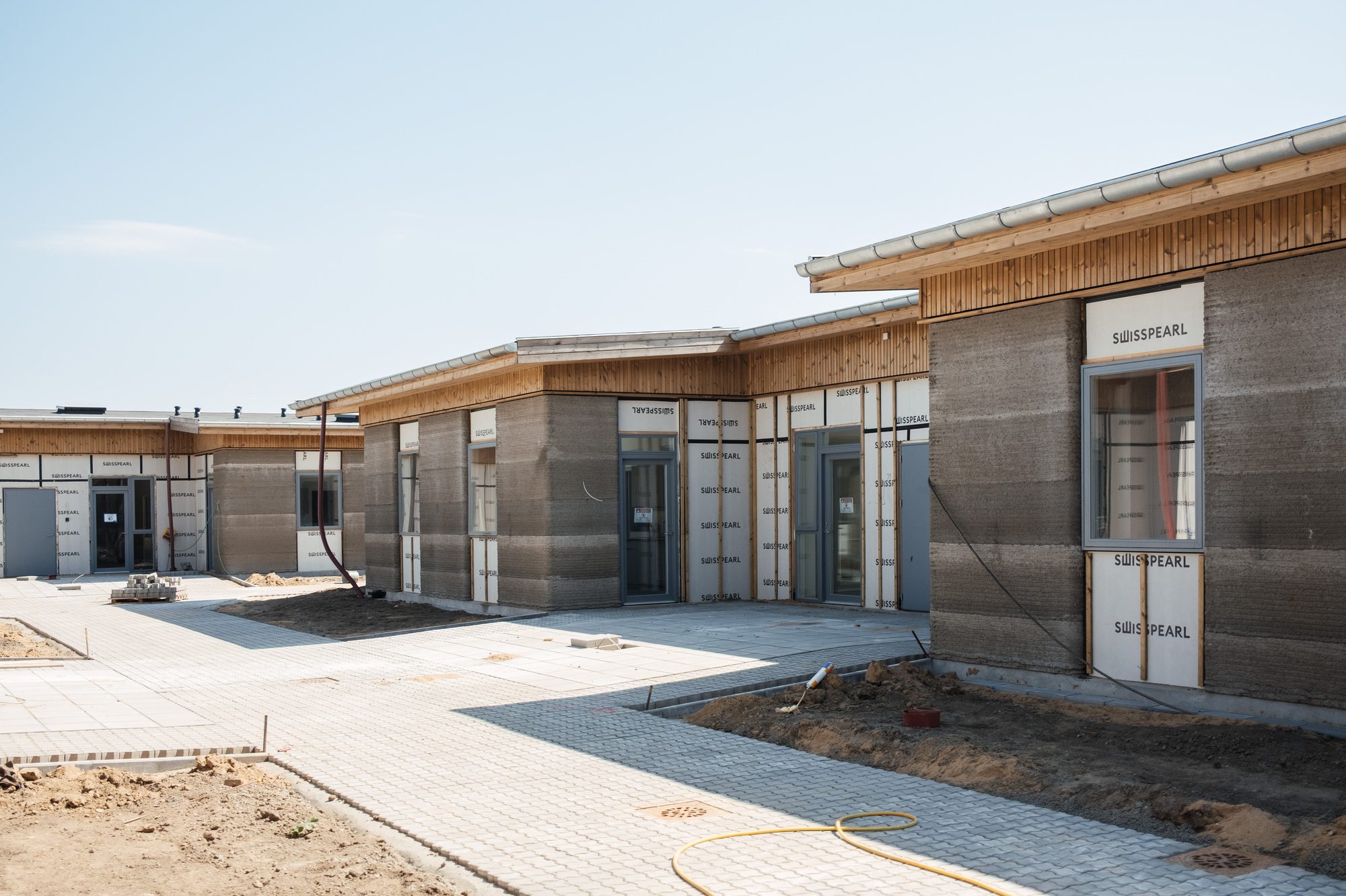 Printed concrete housing units set among retained mature trees on the site
