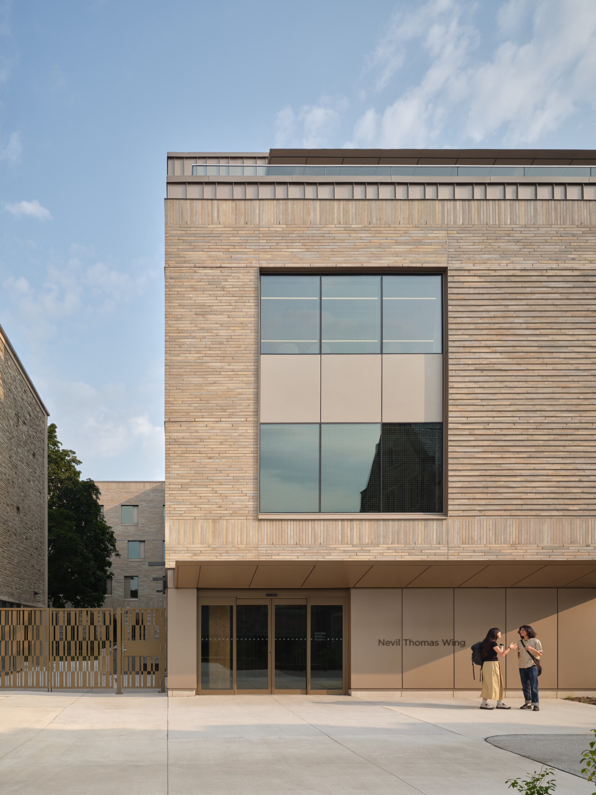 Wide view of the low-rise T-volume set among Neo-Gothic and modernist campus buildings