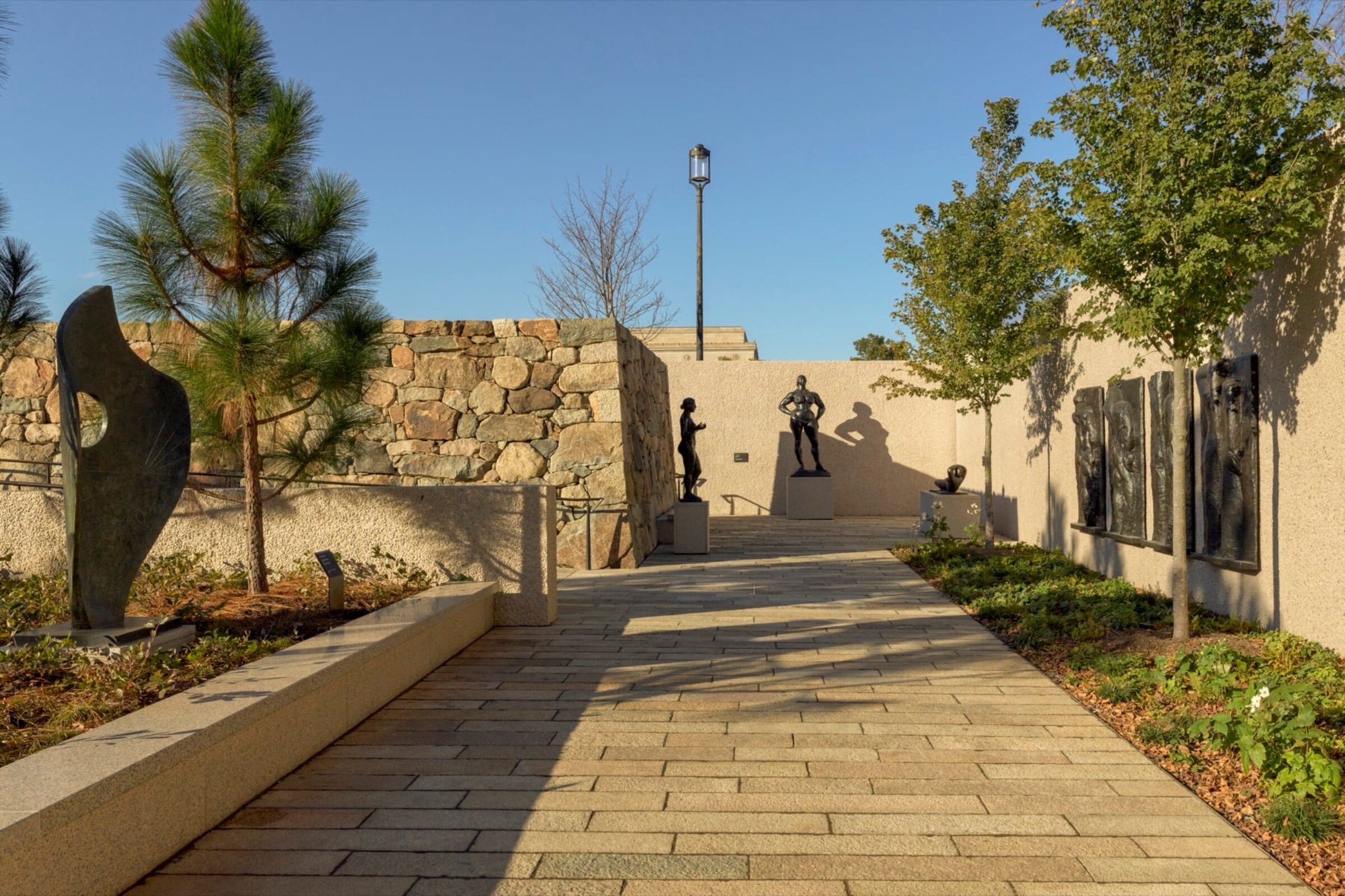 Modern sculpture displayed among trees and stone walls in the Hirshhorn East Garden