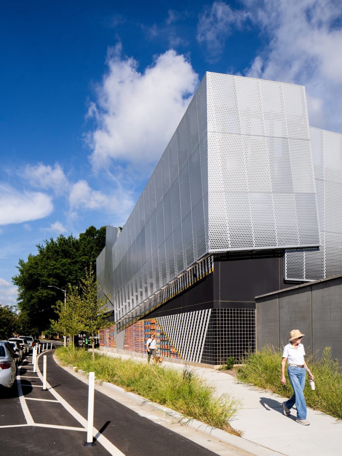 Folded anodized aluminum panels catching daylight above the tiled base